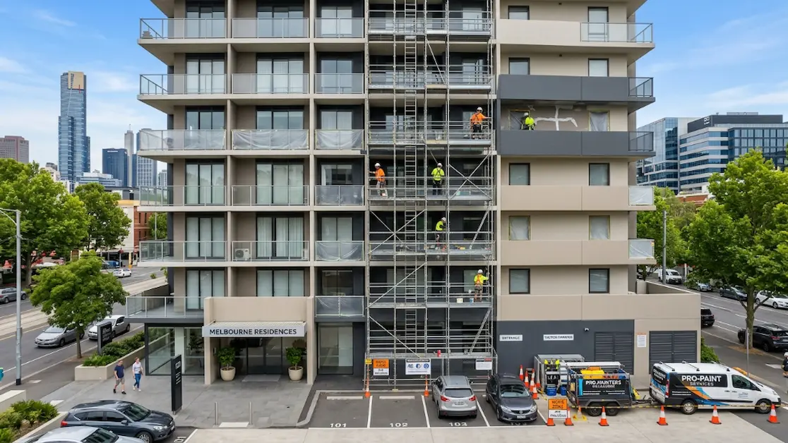 Painters working on a multi-storey residential building using scaffolding to repaint facades and balconies.